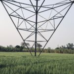 High-voltage transmission tower standing in a green field in rural India