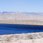 Utility-scale solar panels across a desert landscape below dry mountains