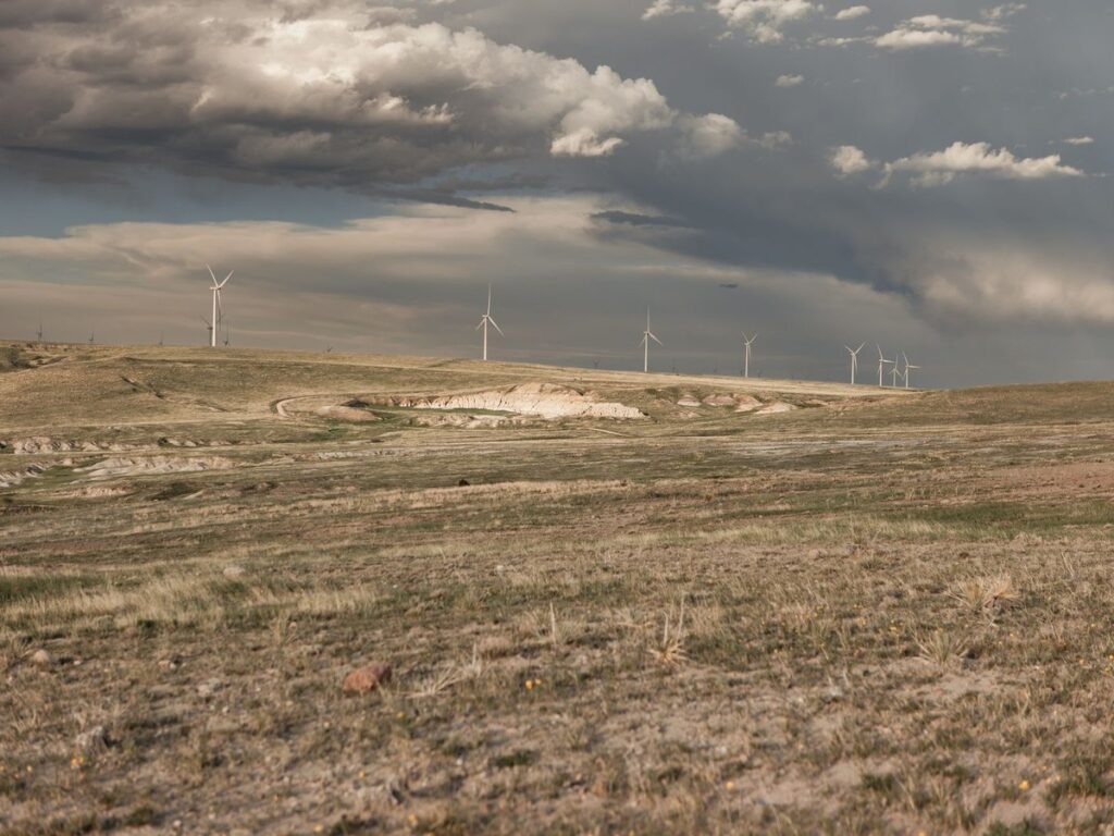 Wind turbines spread across open steppe under a wide cloudy sky