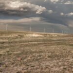 Wind turbines spread across open steppe under a wide cloudy sky