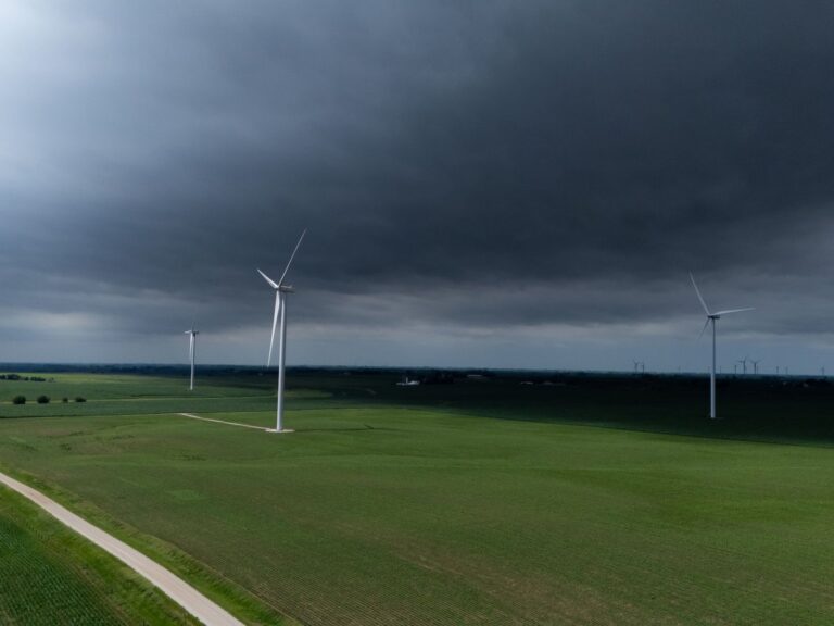 Wind turbines generating power across green fields under a stormy sky